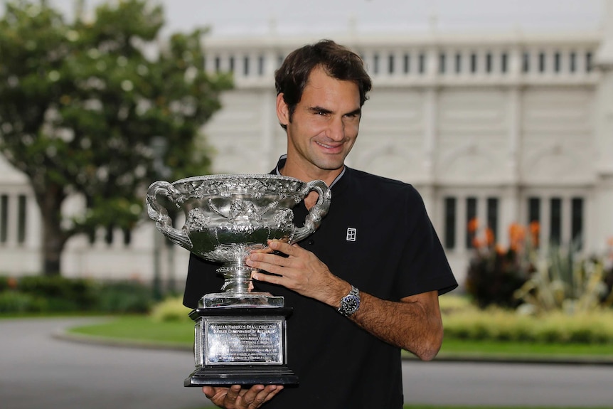 Roger Federer poses with the Australian Open trophy in Carlton Gardens in Melbourne