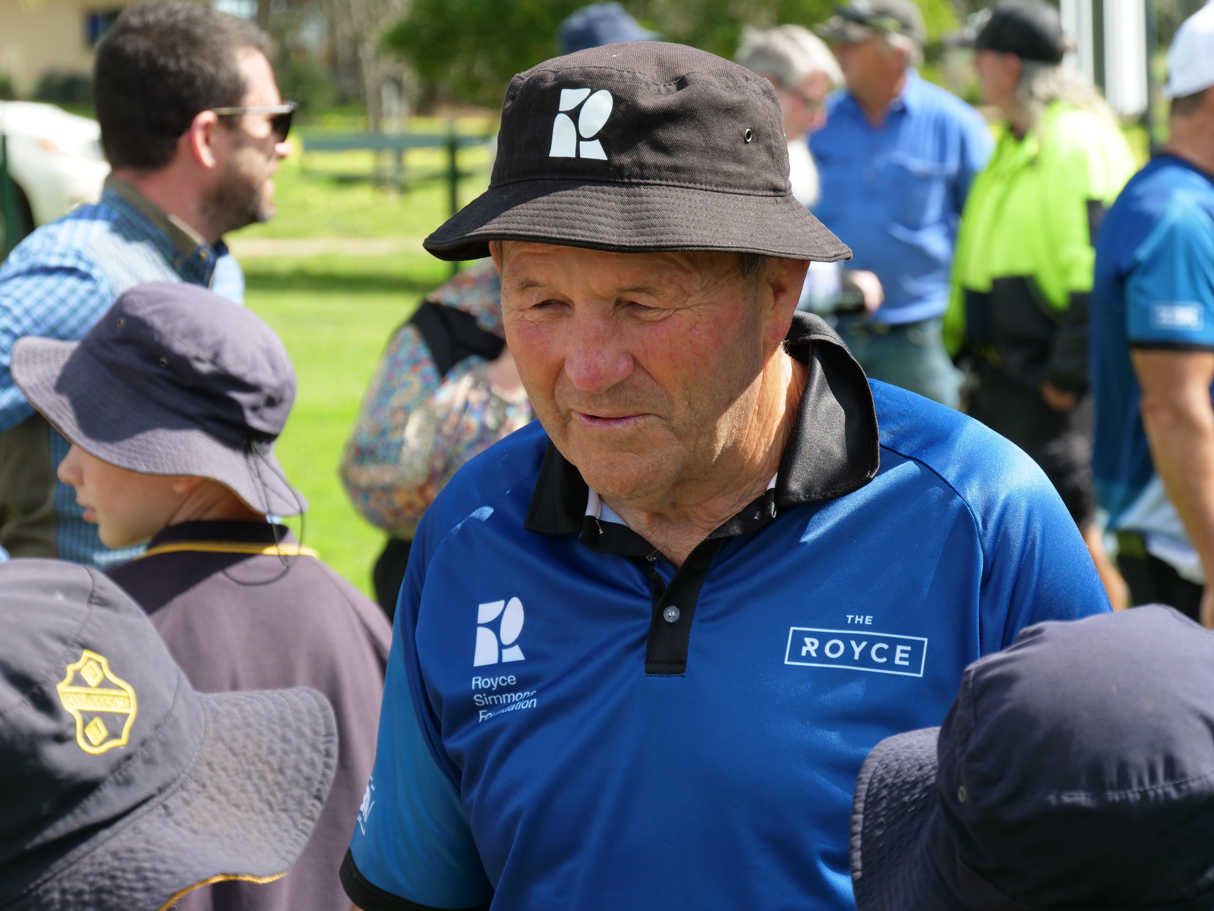 Royce Simmons wearing a hat standing next to school children