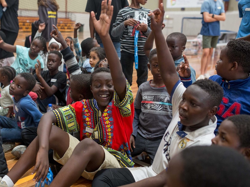 Kids excitedly put up their hands on the basketball court.