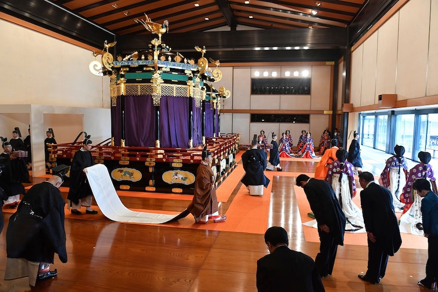 A colourful throne in the middle of a hall.