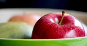 Closeup of red apple in green ceramic bowl