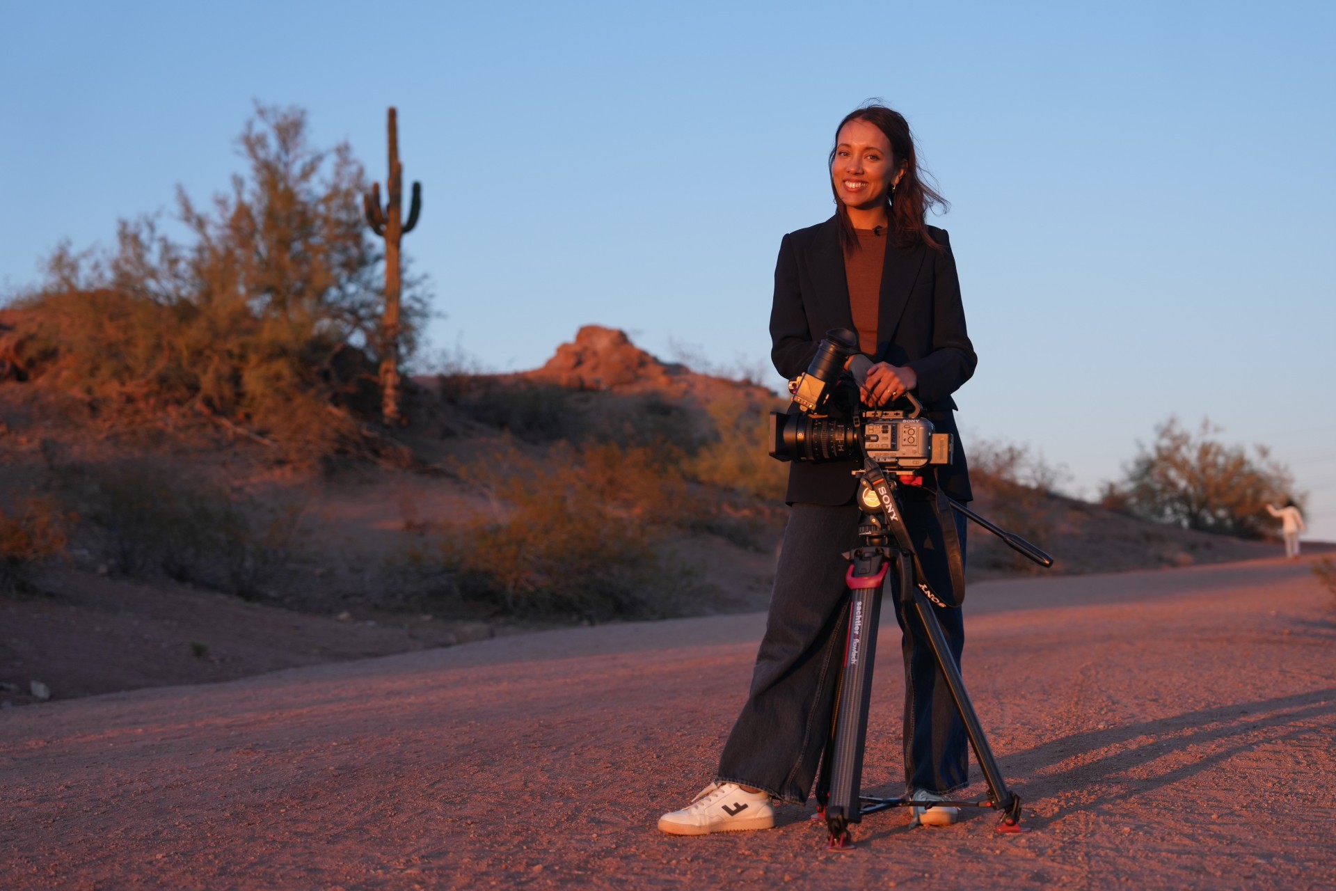 Una mujer de unos treinta años, con cabello largo y castaño y ojos marrones, se encuentra frente al desierto de Arizona y sostiene una cámara en la mano.