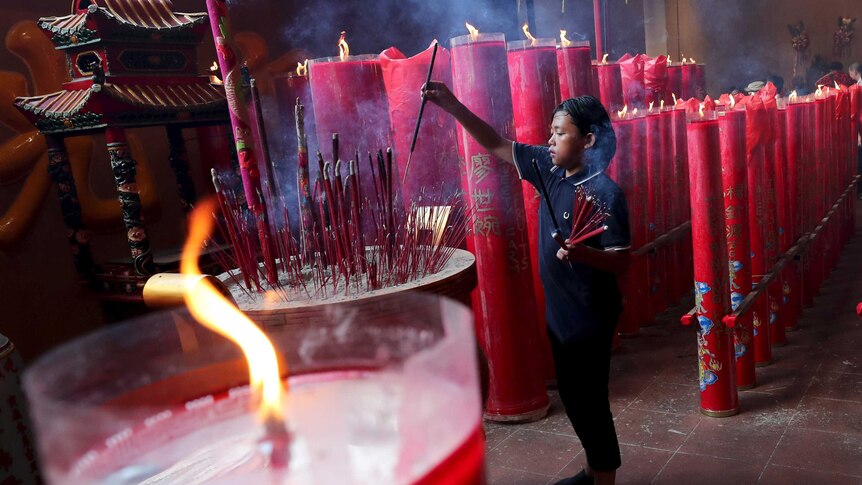 An Indonesian of Chinese descent holds joss sticks during a celebration of the Lunar New Year at a temple in Jakarta.