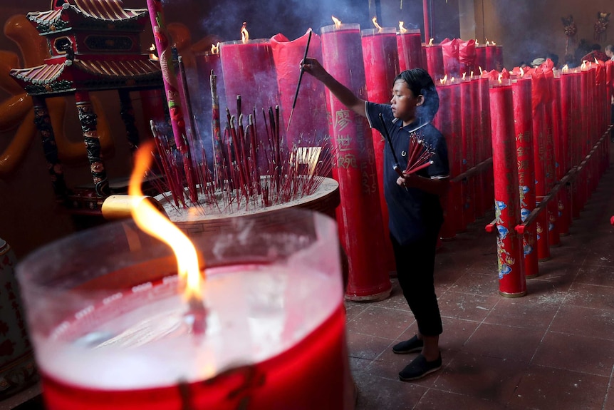 An Indonesian of Chinese descent holds joss sticks during a celebration of the Lunar New Year at a temple in Jakarta.