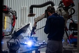 Operator uses welding machine at manufacturing facility.