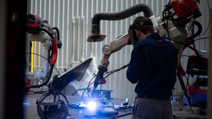 Operator uses welding machine at manufacturing facility.