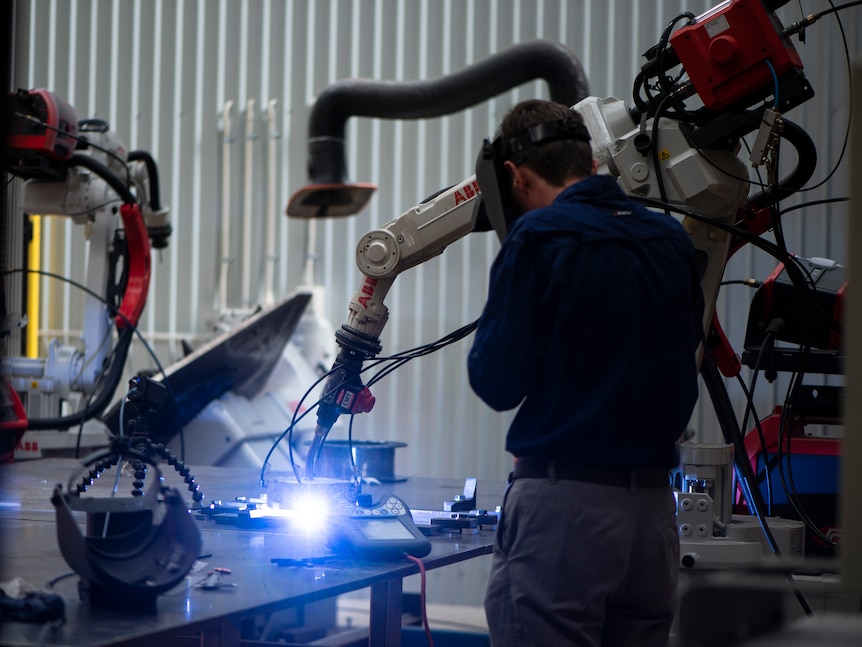 Operator uses welding machine at manufacturing facility.