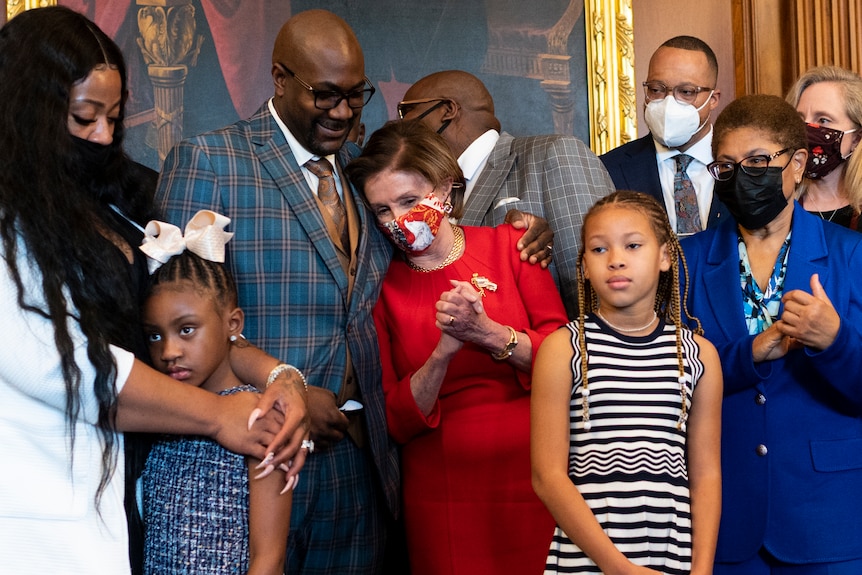 Nancy Pelosi is hugged by Philonese Floyd, surrounded by other family members. 