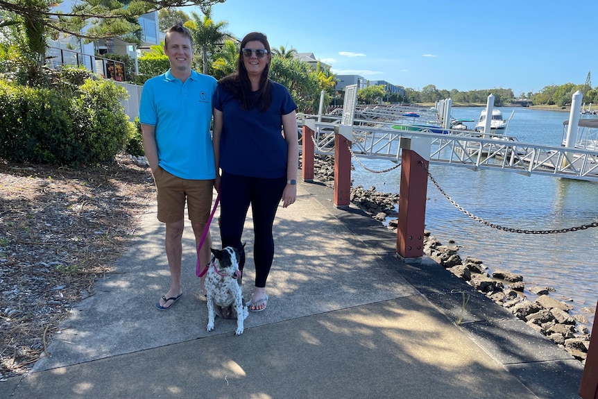 man, woman and dog stand together for photo with canal in the background