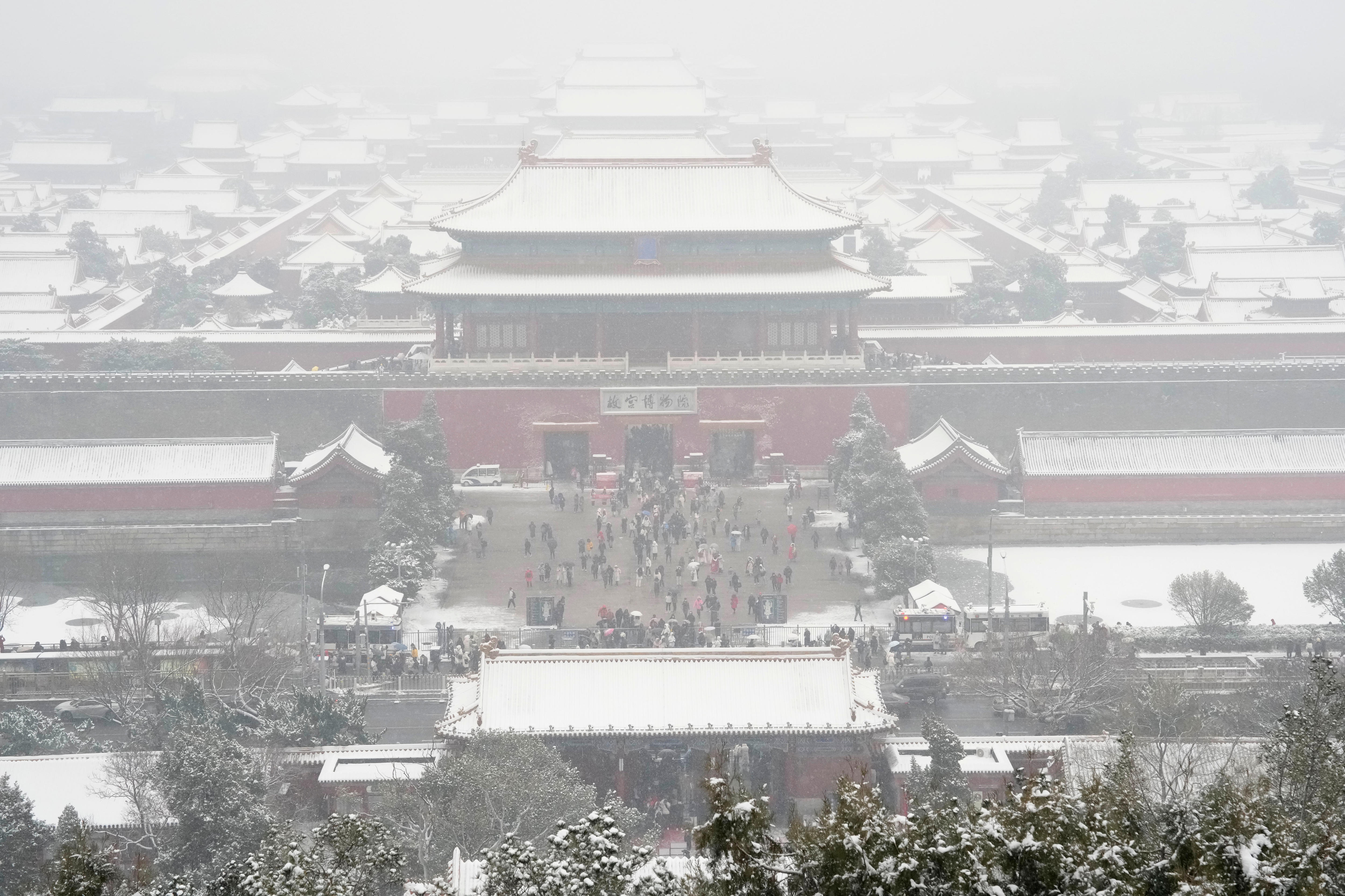 traditional chinese-style buildings that make up the forbidden city complex covered in snow in a haze