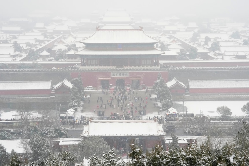 traditional chinese-style buildings that make up the forbidden city complex covered in snow in a haze