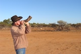 Greg blows a bulls horn to call in wild dogs