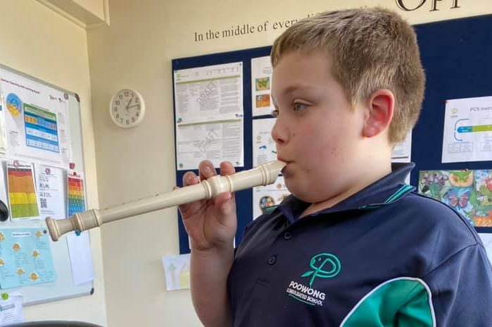 A young boy plays the recorder