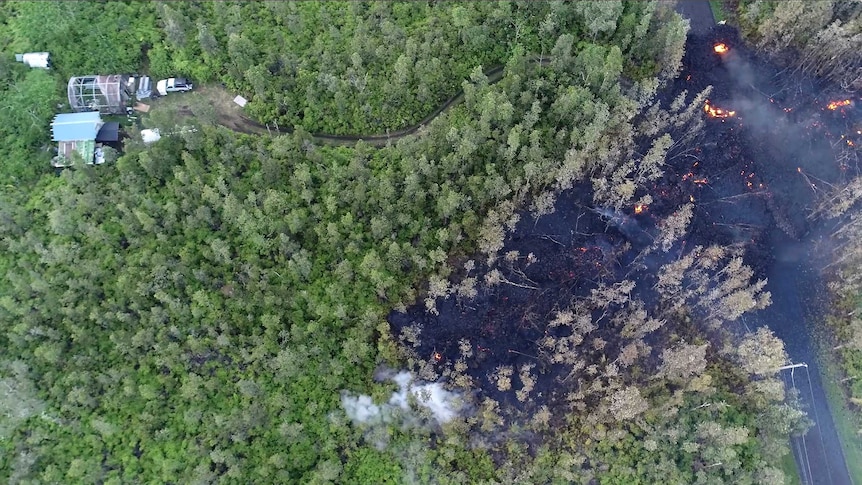 Lava flows toward a home in the Puna District.