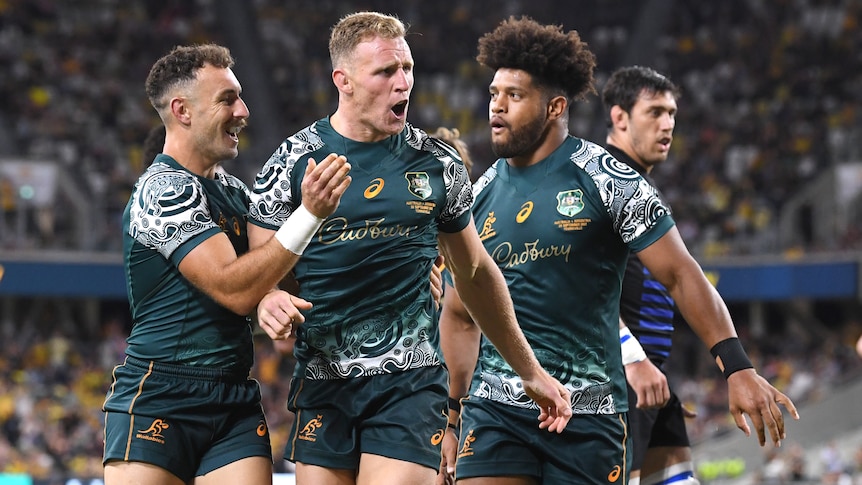 Three Wallabies players celebrate a try against the Pumas.