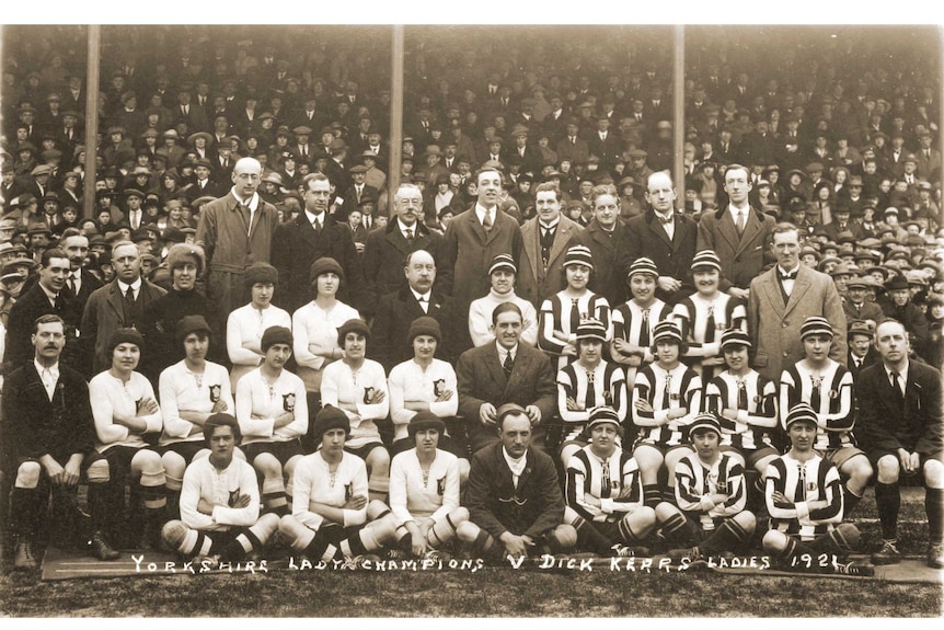 Two women's football teams are pictured in front of a crowd of spectators