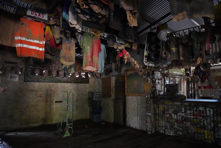 A range of mud-covered shirts and other memorabilia hang on the wall next to a muddy bar.