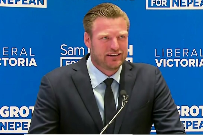 Former tennis player Sam Groth speaking in front of a Liberal Party wall.