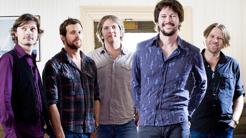 Five members of Powderfinger smile at the camera