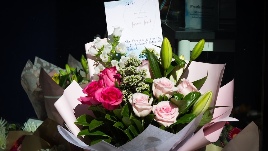 A bouquet of roses with a card stuck in the middle outside St Andrew's Cathedral School in Sydney