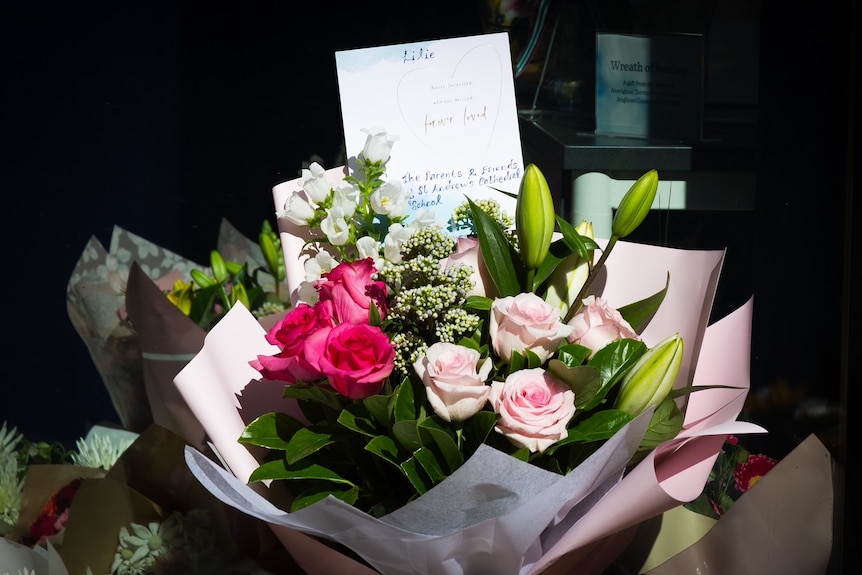 A bouquet of roses with a card stuck in the middle outside St Andrew's Cathedral School in Sydney