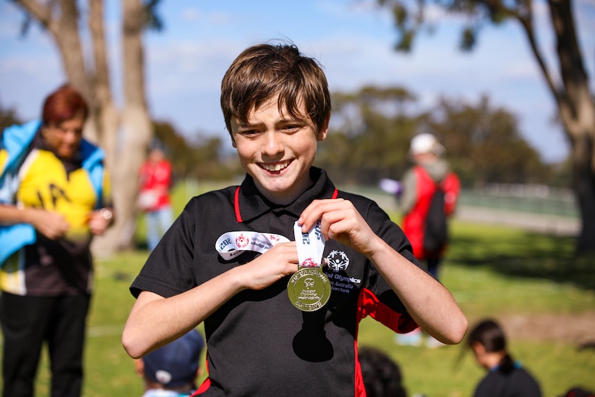 Special Olympics competitor Reece holds up his medal.