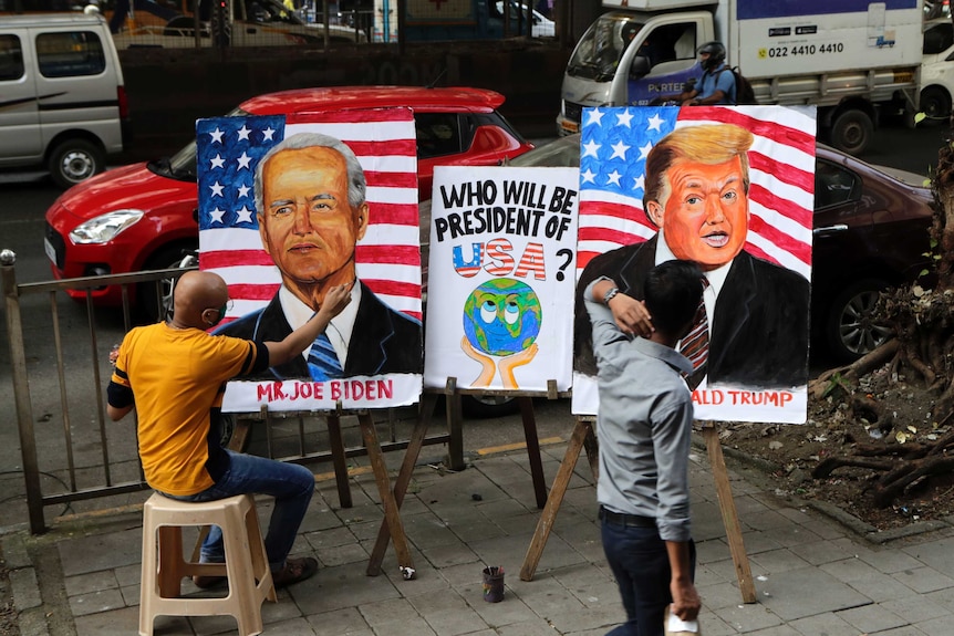 Separate artworks of President Donald Trump and Democratic rival Joe Biden sit side by side on easels on a street