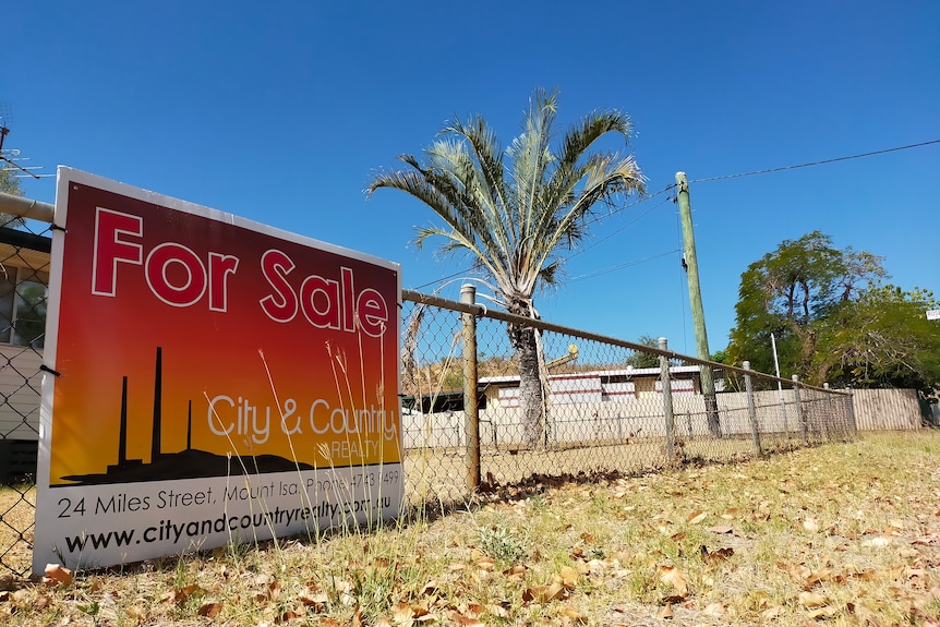 A for sale sign on the gate of a house