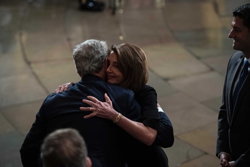 Democratic House leader Nancy Pelosi and former president George W Bush embrace.