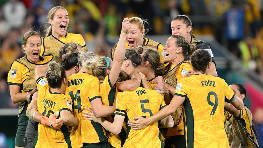 A group of Matildas footballers jump together in delight, celebrating a big win at the Women's World Cup.