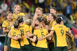A group of Matildas footballers jump together in delight, celebrating a big win at the Women's World Cup.