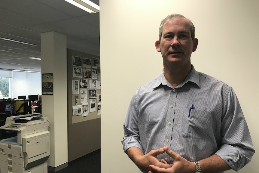 Mick Curran standing in front of a blank wall in an office.