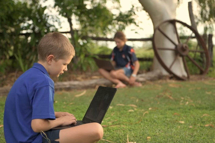 child sitting on lawn with laptop