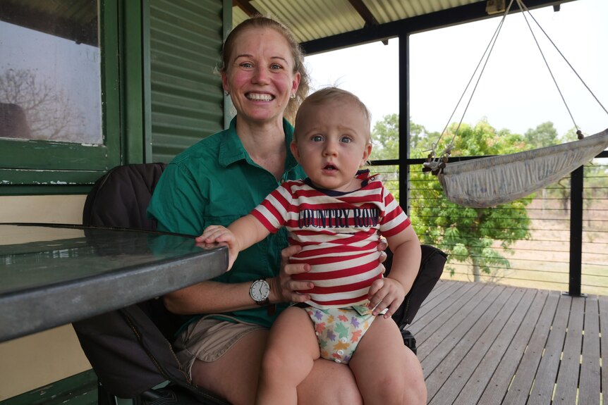 A mum holds a toddler on a veranda 