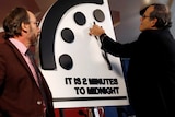 A scientist moves the hands of a model of the Doomsday Clock to two minutes until midnight.