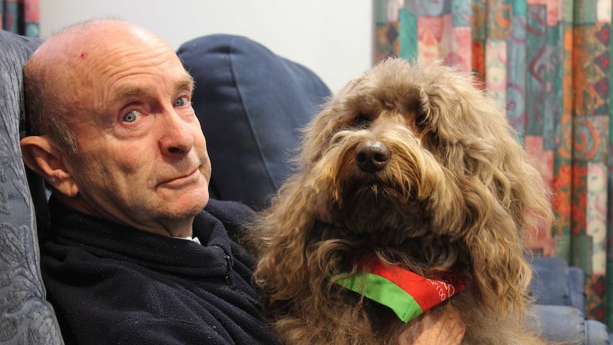 Tim Brickhill with Bailey sitting on his lap at the supportive accommodation.