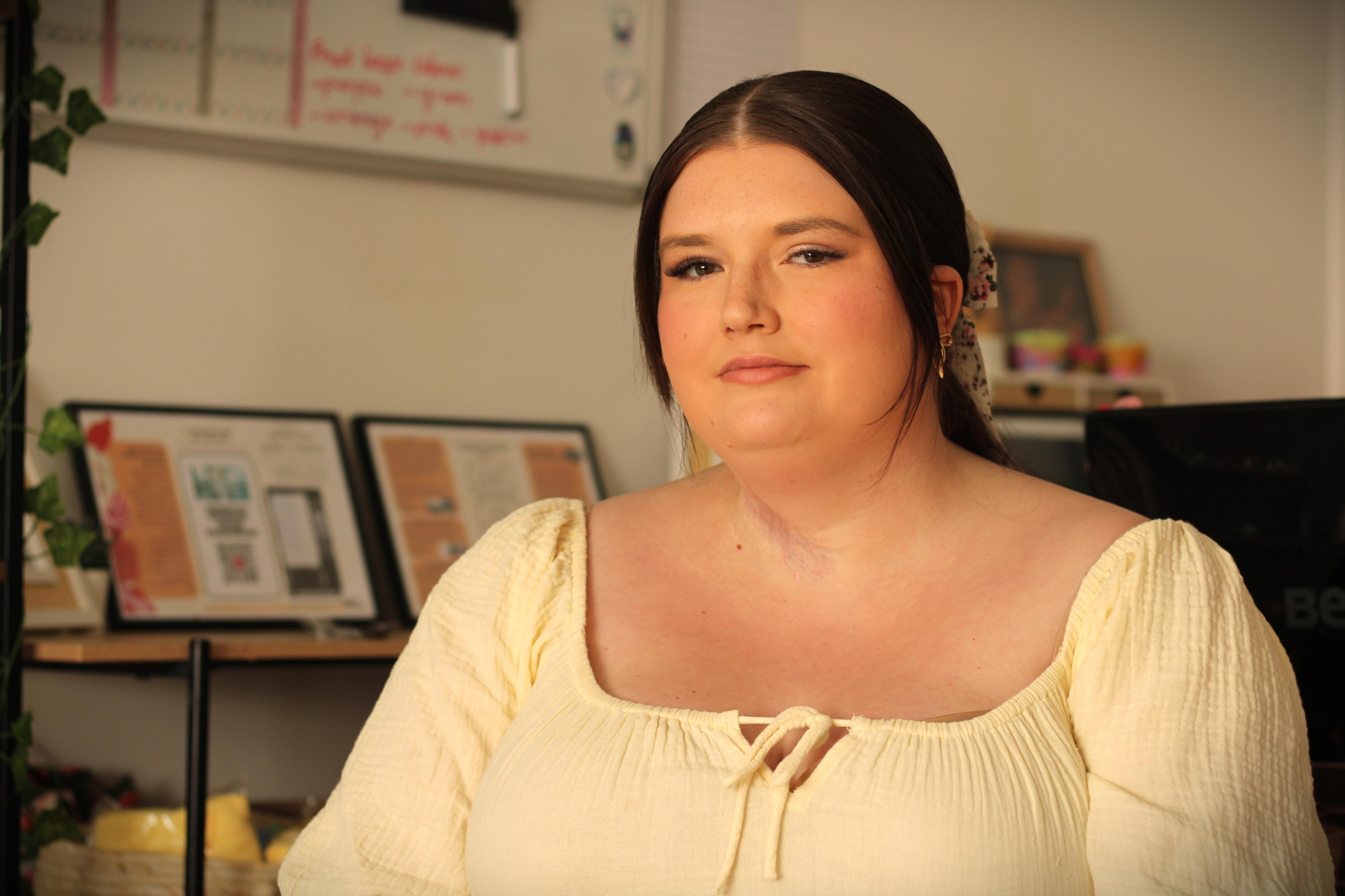 Mulher com cabelo castanho e vestido amarelo sorri para a câmera