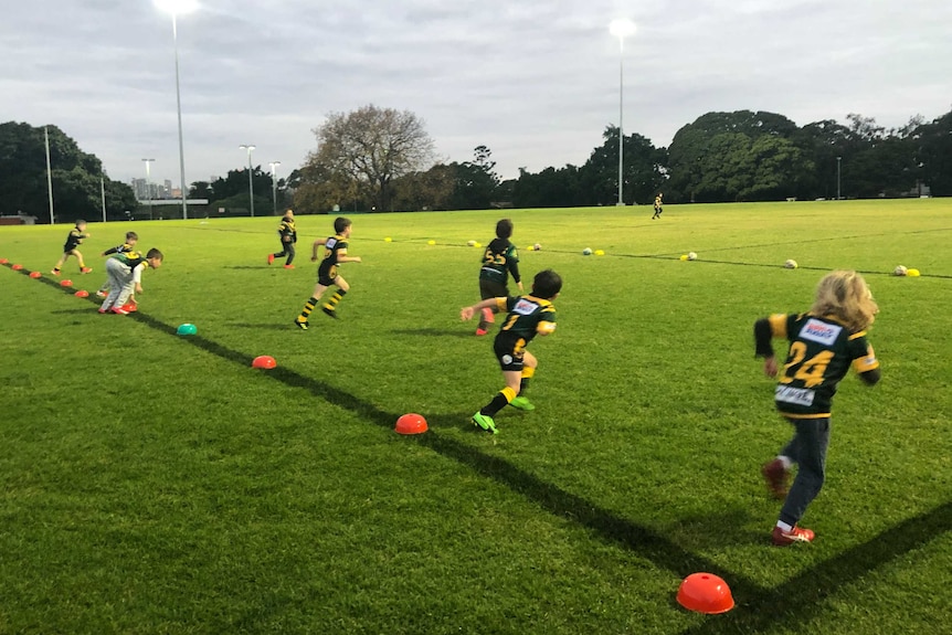 Kids line up to run up a rugby league field.