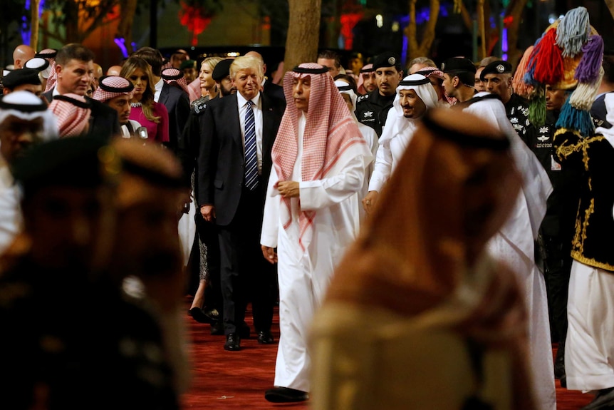 Saudi Arabia's King Salman and Mr Trump walk through a packed function room during a welcome ceremony at Al Murabba Palace