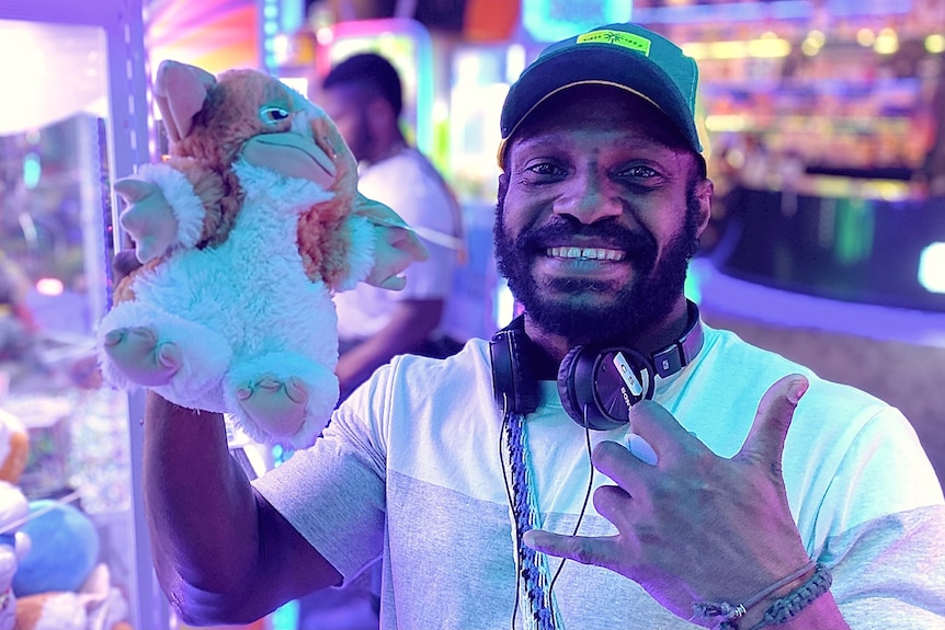 A man holds up a toy in an arcade.