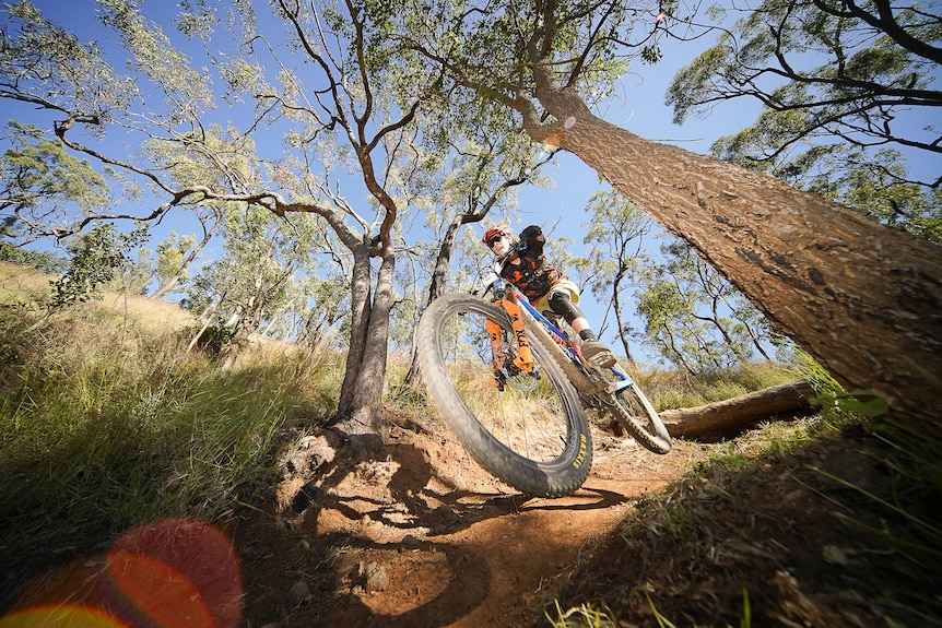A mountain biker on a trail. The image is taken from down low, so the front wheel looks big.