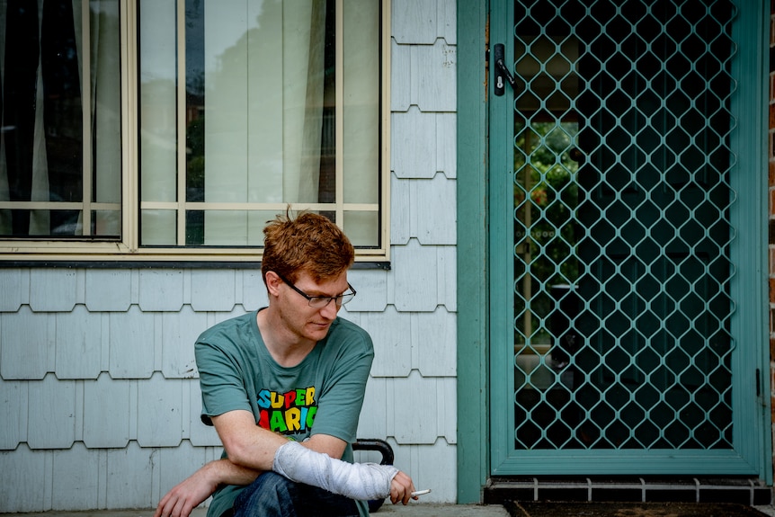 A young man smoking on the porch.