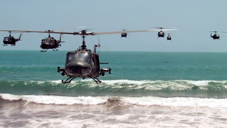 A still of grey helicopters flying low over the ocean from the film Apocalypse Now.