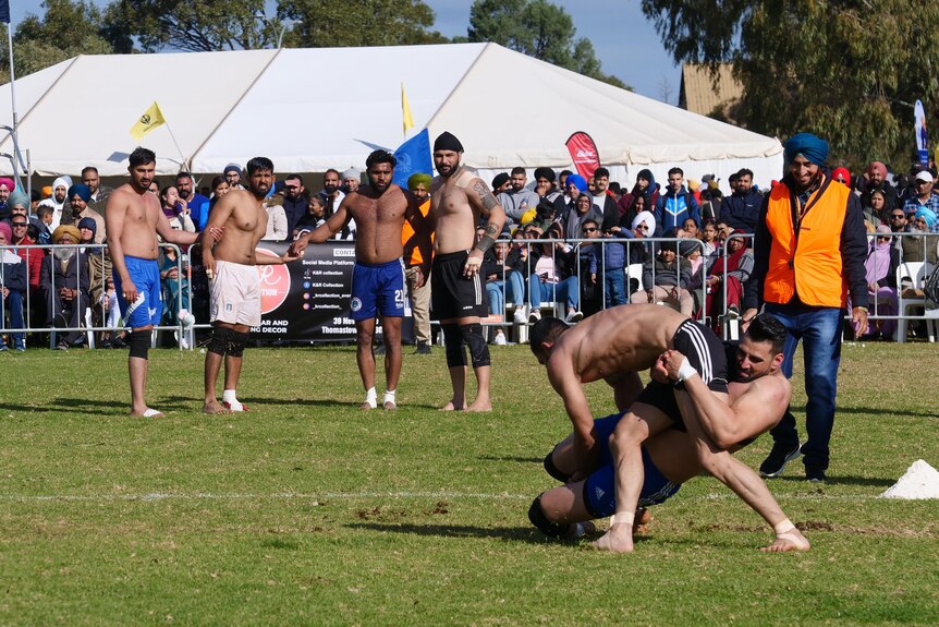 A man tackles another man in front of a crowd