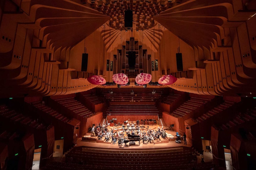 Wide shot of the grand interior of the Concert Hall with lots of seating, big stage and high, acoustically augmented ceiling.