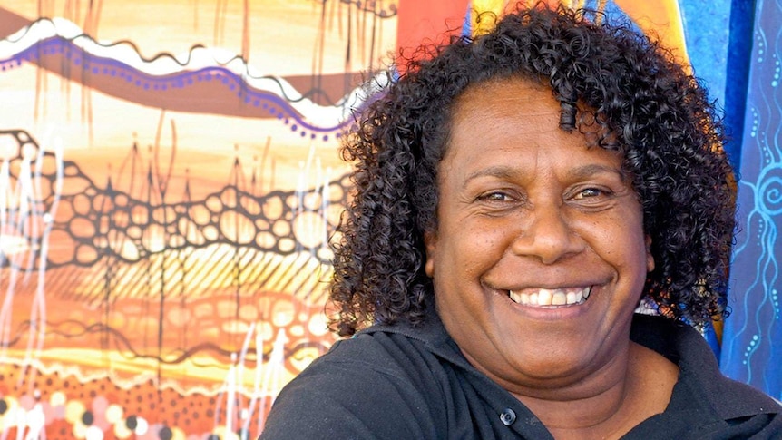 Smiling Torres Strait Islander woman with art backdrop