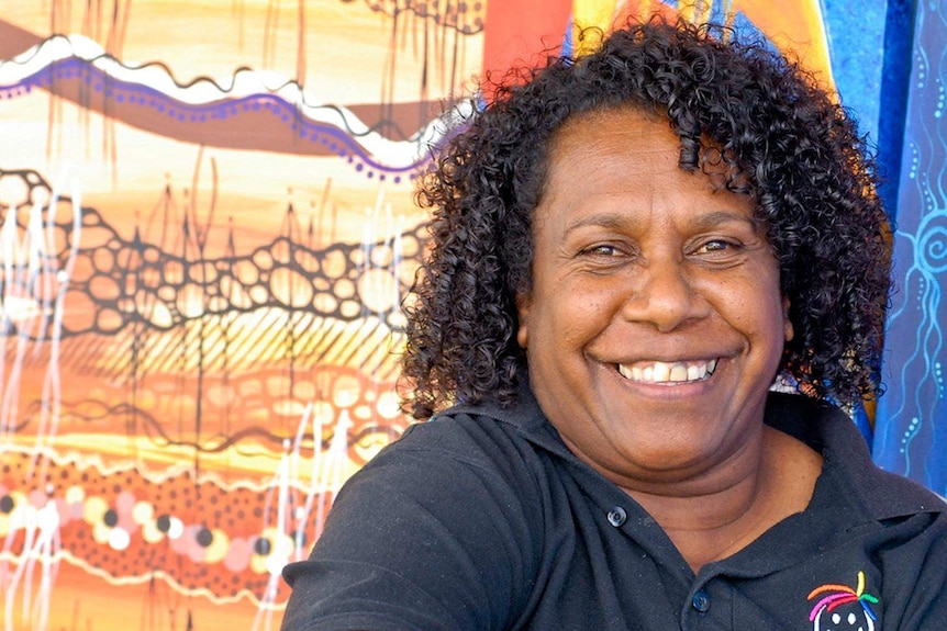 Smiling Torres Strait Islander woman with art backdrop