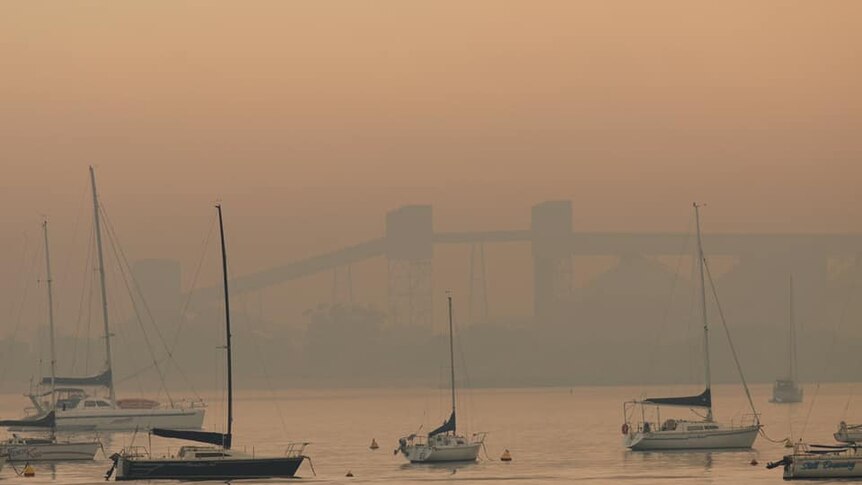 A thick haze of smoke sits over a harbour