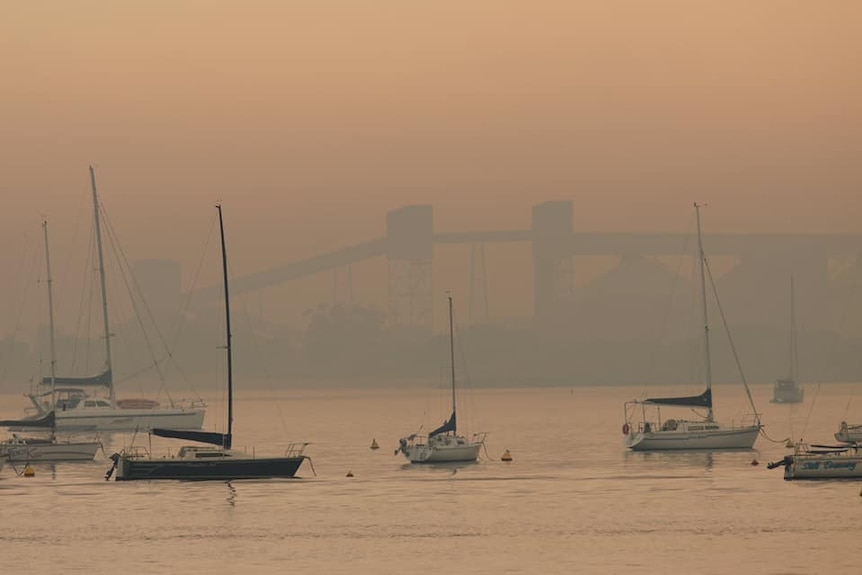 A thick haze of smoke sits over a harbour