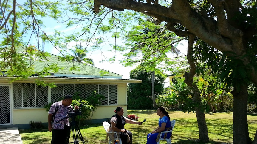 Photo of a camera operator filming an interview with a female journalist and female interviewee